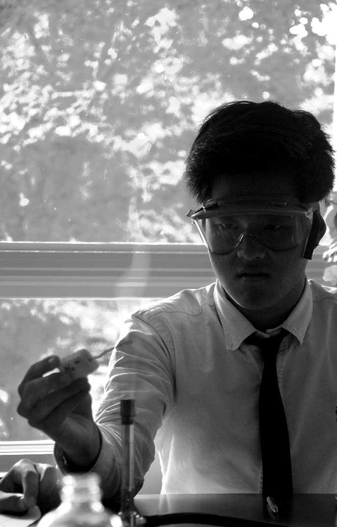 A student performing a science experiment near a window in black and white